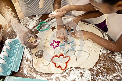 Father and daughters having hands in flour while making cookies Stock Photo