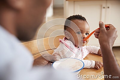 Father Feeding Baby Daughter In High Chair Stock Photo