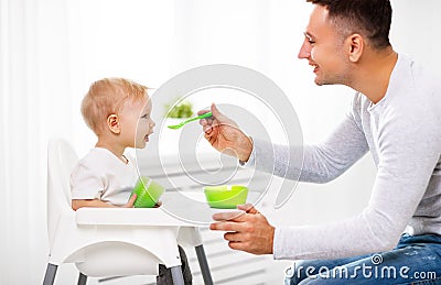 Father feeds baby from spoon Stock Photo