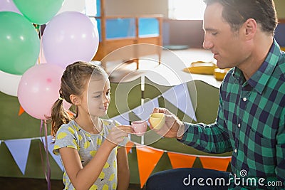 Father and girl toasting their tea cups while playing with toy kitchen set Stock Photo