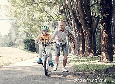 Father help his son learn to ride bicycle Stock Photo