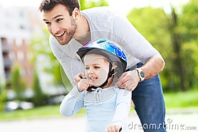 Father helping daughter with bike helmet Stock Photo