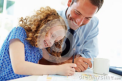 Father Helping Daughter With Homework In Kitchen Stock Photo