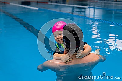 Father helping his little daughter overcome fear of swimming. Young father teaching his fearful daughter how to swim in Stock Photo