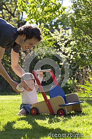 Father helping his son in garden to take his first step of life Stock Photo