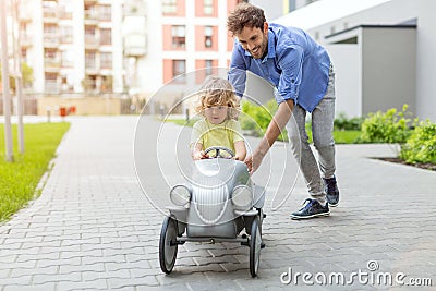 Father helping his son to drive a toy peddle car Stock Photo