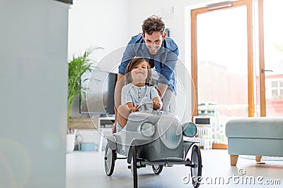 Father helping his son to drive a toy peddle car Stock Photo