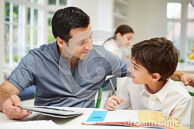 Father Helping Son With Homework Using A Tablet Stock Photo