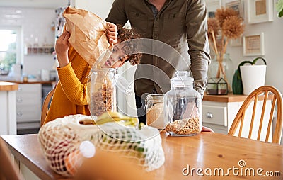 Father Helping Son To Refill Food Containers At Home Using Zero Waste Packaging Stock Photo