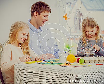 Father and his daughter painting and decorating easter eggs.family having fun and enjoying flavored tea and cupcakes. Stock Photo