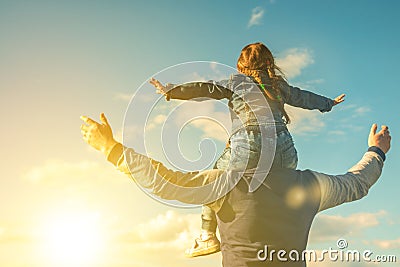 Father and his daughter playing outdoors. the child sits at the daddy on the neck, having lifted hands. Stock Photo