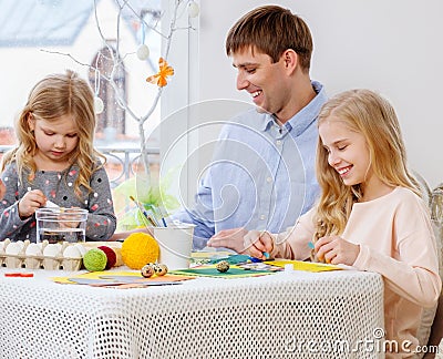 Father and his daughters painting and decorating easter eggs. Stock Photo