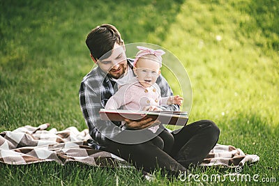 Father and his little baby daugter reading book in a park Stock Photo