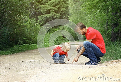 Father and his toddler son found the insect and inspect it. Kid exploring nature concept. Copy space Stock Photo