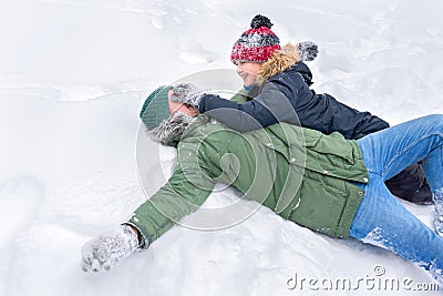 A father with his 10-year old son is playing with the snow lying in the snow Stock Photo