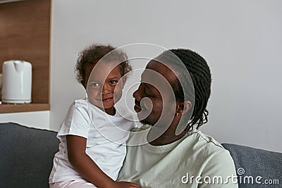 Father hugging joyful daughter on sofa at home Stock Photo