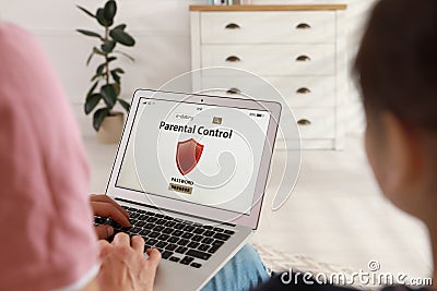 Father installing parental control app on laptop to ensure his child`s safety at home, closeup Stock Photo