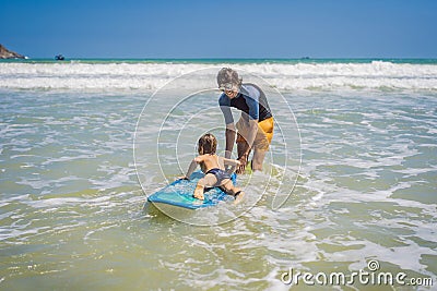 Father or instructor teaching his son how to surf in the sea on vacation or holiday. Travel and sports with children Stock Photo