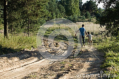 Father learning his son to ride on bicycle outside Stock Photo