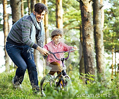 Father learning his son to ride on bicycle outside, real happy family, lifestyle people concept Stock Photo