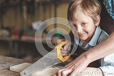 Father and a little son sawing a board Stock Photo