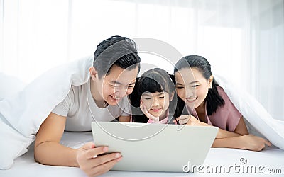 Father and mother with daughter relaxing and using laptop on bed Stock Photo