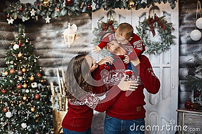 The father and mother holds their little son and posing near the Christmas tree. Concept of family holiday. Young Stock Photo