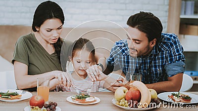 Father and Mother Teach Little Girl Eat Cutlery. Stock Photo