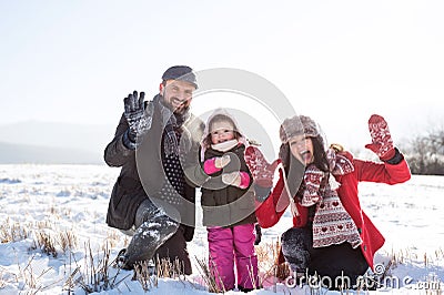 Father and mother with their daughter, playing in the snow. Stock Photo