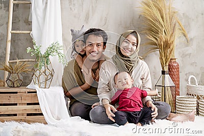 Father, mother and two children comfortably sit on the carpet with smile Stock Photo