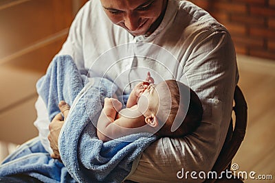 Father With Newborn Baby Working From Home Using Laptop Stock Photo