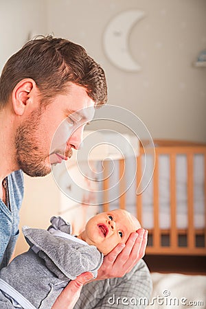 Father and newborn in Scandi bedroom interior. The father sings a lullaby to the child. Parent calms the baby before going to bed Stock Photo