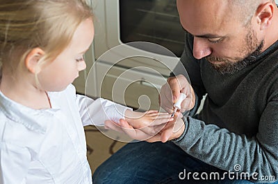 Father painting daughters finger nails Stock Photo