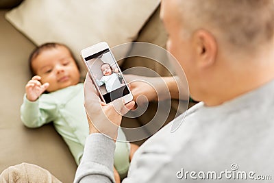 Father photographing baby by smartphone Stock Photo