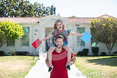 Father piggyback ride supports and motivates son. Kids education. Kid going to primary school. Stock Photo