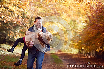 Father Playing Game Carrying Daughter On Family Walk Along Track In Autumn Countryside Stock Photo