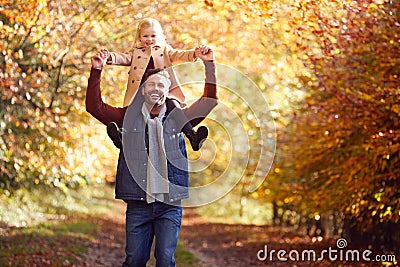 Father Playing Game Carrying Daughter On Shoulders On Family Walk Along Track In Autumn Countryside Stock Photo