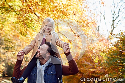Father Playing Game Carrying Daughter On Shoulders On Family Walk Along Track In Autumn Countryside Stock Photo