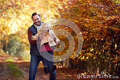 Father Playing Game Picking Up Daughter On Family Walk Along Track In Autumn Countryside Stock Photo