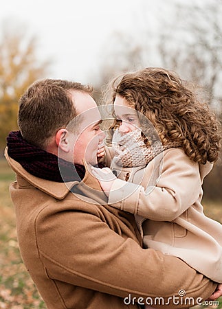 Father plays with her little curly daughter holding her in her arms Stock Photo