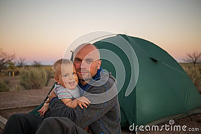 A father plays with his baby son at the tent in campground of Ho Stock Photo