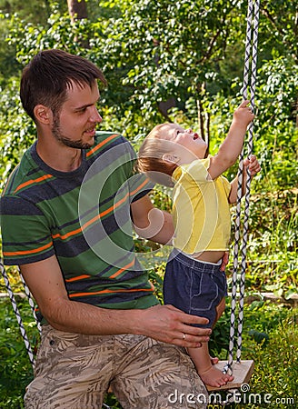 Father plays with his little son on the swing Stock Photo