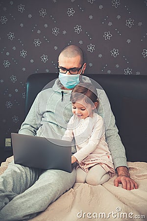 Father in protective mask working from home with his daughter Stock Photo