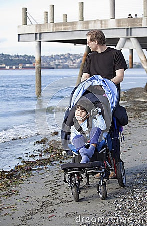 Father pushing disabled son on beach Stock Photo