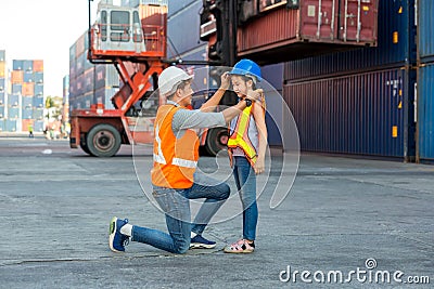 Father puts a safety helmet on little daughter at Container cargo site. Business heir concept. Happy father wearing safety helmet Stock Photo