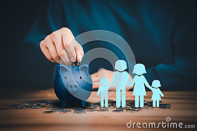 Father putting coins on piggy bank with family icon on the table. Stock Photo