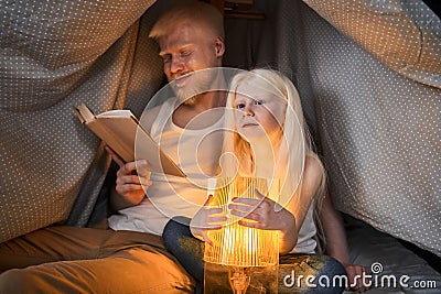 Father reading interesting fairy tales to his blonde cute daughter Stock Photo