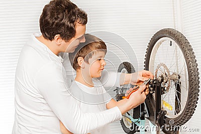 Father repairing brakes of bicycle with his son Stock Photo