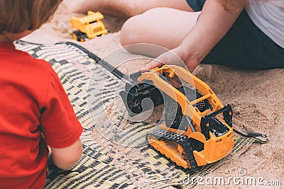 Father`s day. Dad and son. Little son plays toys with dad on the beach with sand. Stock Photo