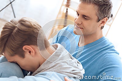 Son was offended by dad and leaned head on knee. Stock Photo